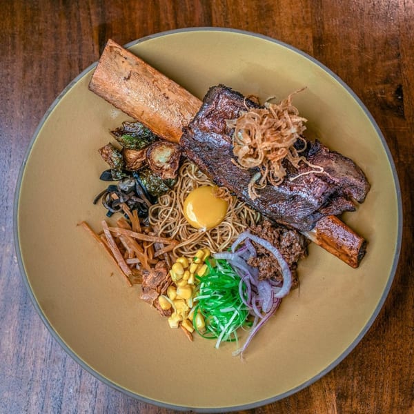 NōKA Ramen & Bar's ramen bowl with a large short rib, egg yolk, corn, and various toppings.