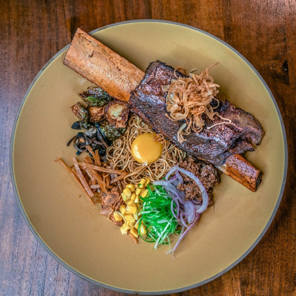 NōKA Ramen & Bar's ramen bowl with a large short rib, egg yolk, corn, and various toppings.