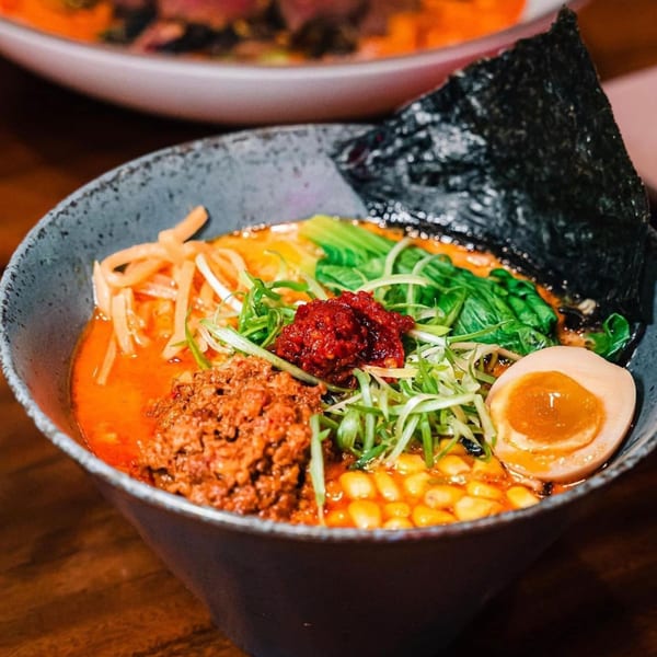NōKA Ramen & Bar's spicy ramen bowl with pork, corn, scallions, nori, and a soft-boiled egg.